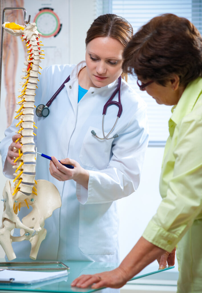 Physical Therapist shows the problem areas on the model of the spine to patient and  explains the cause of her pain.